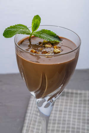 Chocolate cocktail with nuts and mint in a glass on a blue background on a napkin. Vertical photoの写真素材
