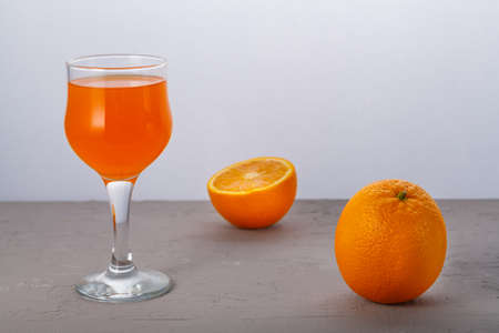 Orange juice in a glass near oranges on a gray background. Horizontal photoの写真素材