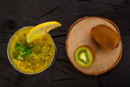 Kiwi smoothie garnished with mint and lemon in a glass on a black background near kiwi top view. Horizontal photoの写真素材
