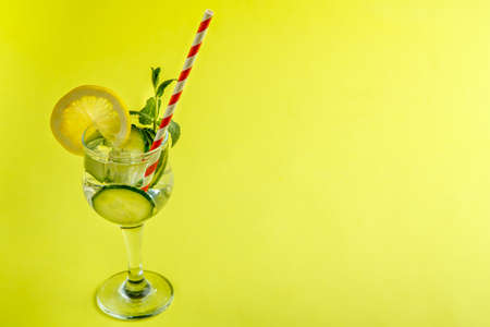 Cocktail cucumber water with lemon and mint in a glass on a napkin on a yellow background. Horizontal photoの写真素材
