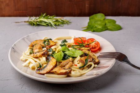 Udon with mushrooms and spinach in a plate on a concrete background next to a fork. horizontal photoの写真素材