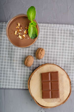 Chocolate cocktail with nuts and mint in a glass on a blue background near nuts and chocolate on a napkin top view. Vertical photoの写真素材