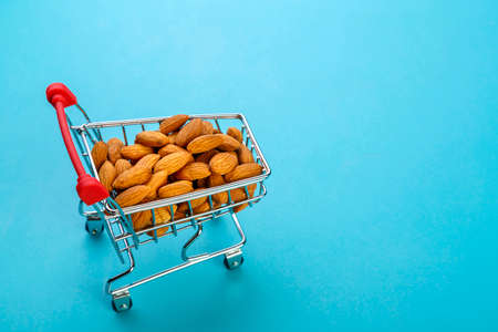 Food cart filled with peeled almonds on a blue background. horizontal photoの写真素材