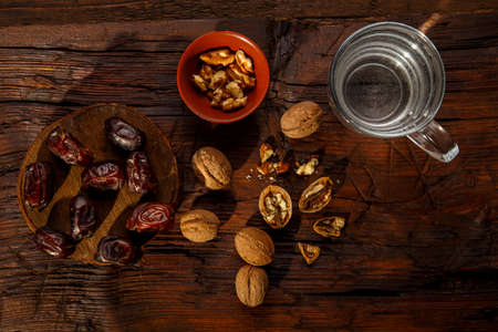 Food for iftar in ramadan on a wooden table dates, nuts and water. Horizontal photoの写真素材