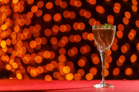 Chocolate cocktail with nuts and mint in a glass against a background of blurry lights. Horizontal photoの写真素材