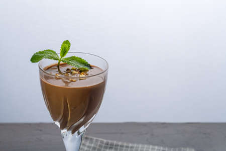 Chocolate cocktail with nuts and mint in a glass on a blue background on a napkin. Horizontal photoの写真素材