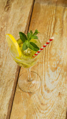 Cocktail with kiwi mint and lemon in a glass on a wooden table. Vertical photoの写真素材