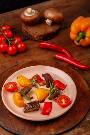 Antipasta on a plate on a stand on a wooden table next to vegetables. Vertical photoの写真素材