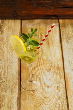Cocktail with kiwi mint and lemon in a glass on a wooden table. Vertical photoの写真素材