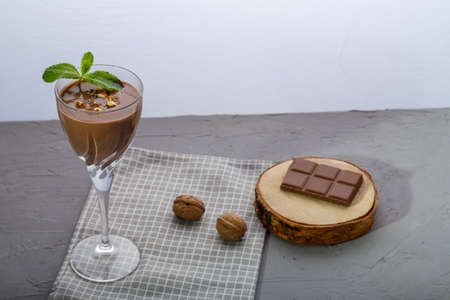 Chocolate cocktail with nuts and mint in a glass on a blue background near nuts and chocolate on a napkin. Horizontal photoの写真素材