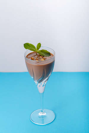 Chocolate cocktail with nuts and mint in a glass on a blue background. Vertical photoの写真素材