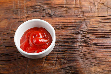 White gravy boat with ketchup on a wooden table. Horizontal photoの写真素材