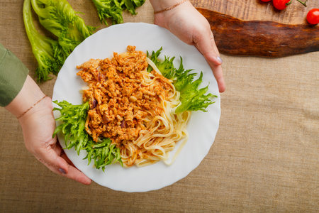A plate of pasta in bolognese sauce in female hands. Horizontal photoの写真素材