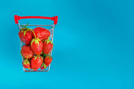 strawberries in a grocery cart on a yellow background. Horizontal photoの写真素材