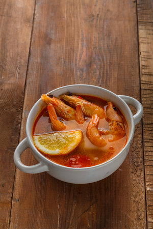 Tom yam soup with shrimps and coconut milk on a wooden table. Vertical photoの写真素材