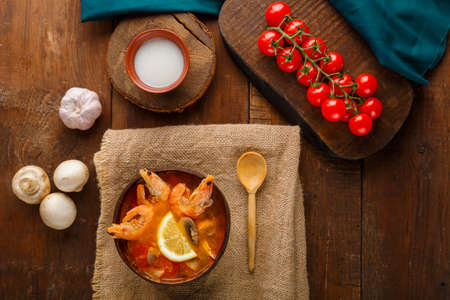 Tom yam soup with shrimps and coconut milk on the table on a napkin next to milk and a wooden spoon. Horizontal photoの写真素材