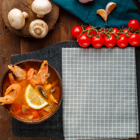 Tom yam soup with shrimps and coconut milk on a wooden table in a plate on a napkin. Square photoの写真素材