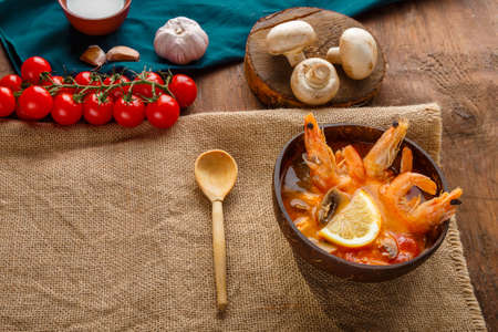 Tom yam soup with shrimps and coconut milk on the table on a napkin next to the ingredients. copy space. Horizontal photoの写真素材
