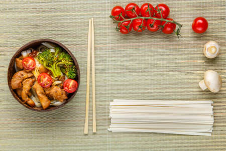 Udon with meat in Japanese sauce on a plate next to vegetables and chopsticks.の写真素材
