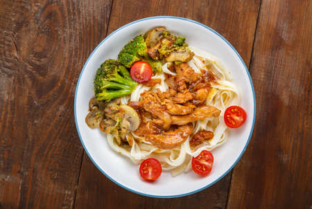 Udon with meat and vegetables in yakiniku sauce in a gray plate on a wooden table. Horizontal photoの写真素材