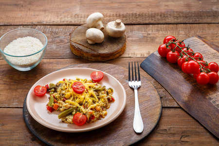 Risotto with bends and cheese in a plate on a wooden background on a round stand next to rice mushrooms and tomatoes on planks. Horizontal photoの写真素材