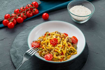 Risotto with beefs and cheese in a plate on a gray background on a black board next to mushrooms, tomatoes and rice. Horizontal photoの写真素材