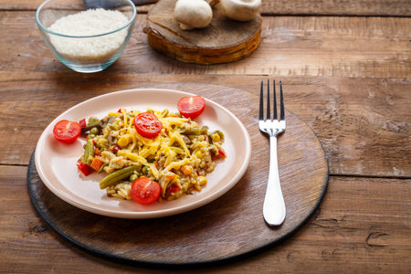 Risotto with bends and cheese in a plate on a wooden background on a round stand next to rice mushrooms and tomatoes on planks. Horizontal photoの写真素材
