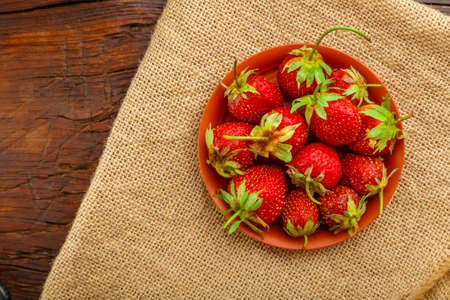 Fresh large strawberries in a clay plate on a linen napkin.の写真素材