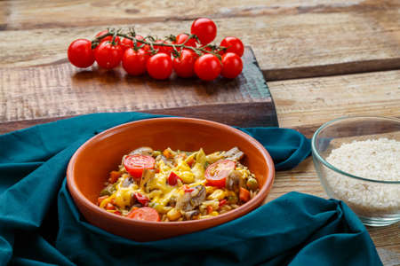 Risotto with mushrooms in a plate on a wooden background on a blue napkin and ingredients. Horizontal photoの写真素材