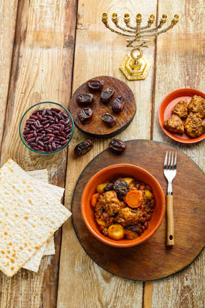 Jewish dish cholent with meat ingredients and menorah on the table. Vertical photoの写真素材