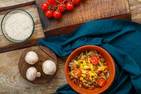 Risotto with mushrooms in a plate on a wooden background on a blue napkin and ingredients.の写真素材