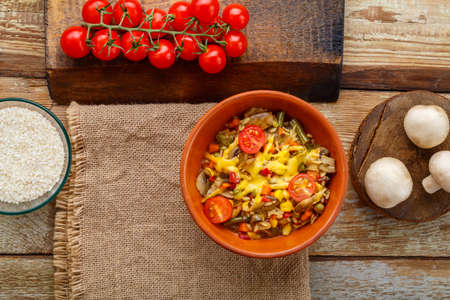 Risotto with mushrooms in a plate on a wooden background on a napkin and ingredients.の写真素材