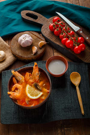 Tom yam soup with shrimps and coconut milk on a table on a black board and a spoon. Vertical photoの写真素材