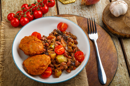Cod cutlets with potatoes and vegetables on a round stand next to the ingredients. Horizontal photoの写真素材