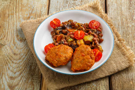 Cod cutlets with stewed potatoes and vegetables on a plate on a napkin. Horizontal photoの写真素材