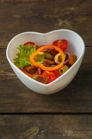 Vegetable vitamin salad in a plate on a wooden table. Vertical photoの写真素材