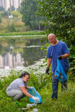 A man and a woman clean up a garbage dump in the nature.の写真素材