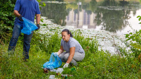 A woman and a man, a faceless volunteer, removes rubbish at a dump in nature.の写真素材