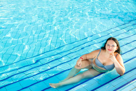Smiling brunette woman lies in the pool. Horizontal photoの写真素材