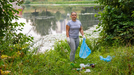 A woman volunteer cleans up garbage at a dump in the park.の写真素材