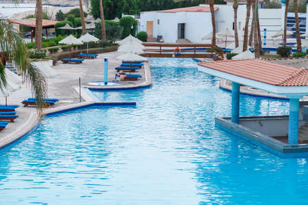 Swimming pool with sun loungers on site next to the sea.