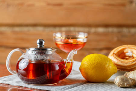 A kettle of strong hot tea on the table on a napkin next to lemon, ginger and jam. Horizontal photoの写真素材