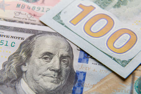 Close-up of dollar bills of one hundred dollar fragments spread out on the table.