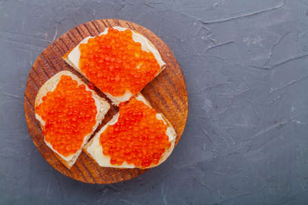 Bruschetta with red caviar on a wooden board on a gray background. Copy place.の写真素材