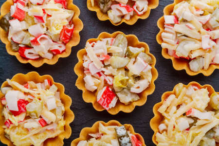Salad with crab in tartlets on a black background close-up.の写真素材