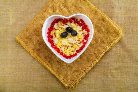 Puff salad with pineapple in a salad bowl decorated with pomegranate on a table on a linen napkin.の写真素材