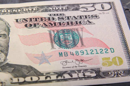 Fragments of fifty dollar bills with a protective strip on a flat surface, very close-up.