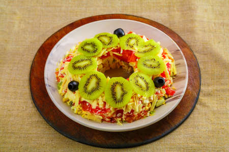 Chicken breast puff salad garnished with kiwi and olives in a salad bowl on a tablecloth. horizontal photoの写真素材