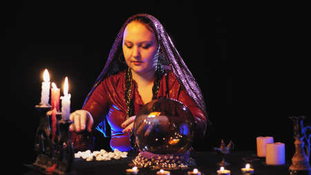 a fortuneteller in a trance read the future in a crystal ball and white stones. overall plan