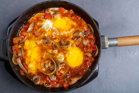 Shakshuka with mushrooms in a frying pan on a gray background. horizontal photo